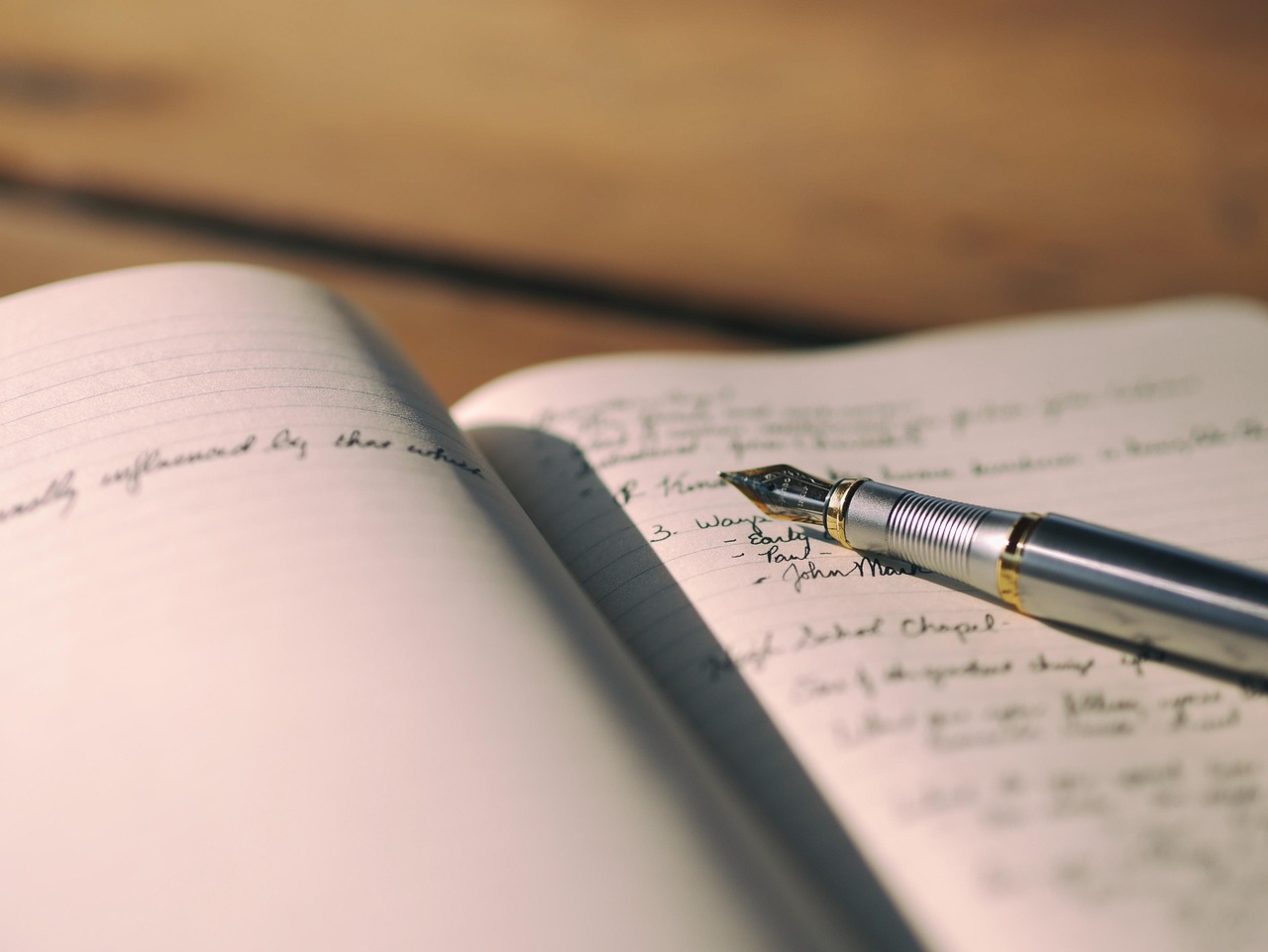 Person writing in a journal, pen on paper